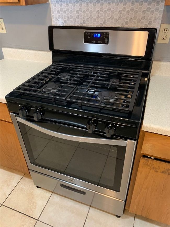 Room details with decorative backsplash, brown cabinets, and stainless steel gas range | Image 4