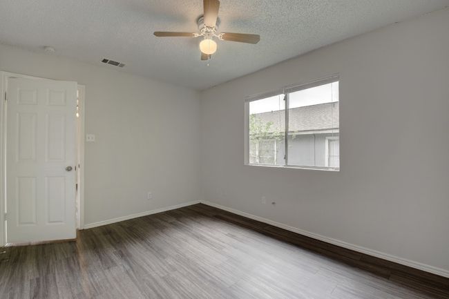 Spare room featuring wood finished floors, a ceiling fan, baseboards, a textured ceiling, and a smoke detector | Image 14