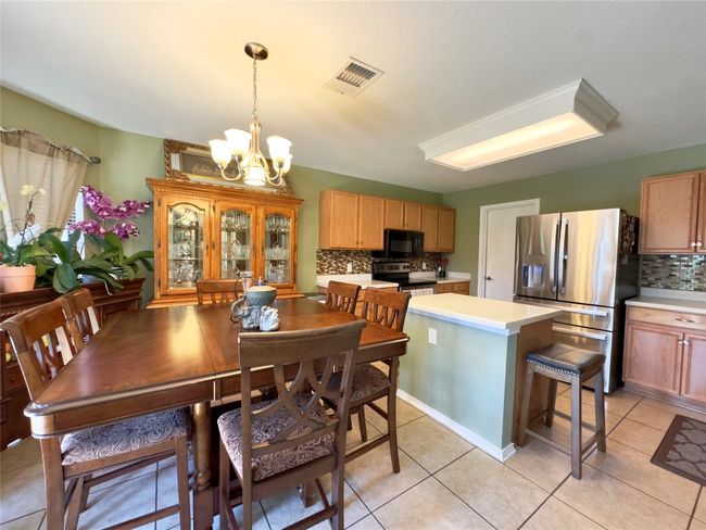 Dining space with a chandelier and light tile patterned flooring | Image 9