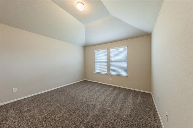 Unfurnished room with dark carpet, lofted ceiling, and baseboards | Image 9