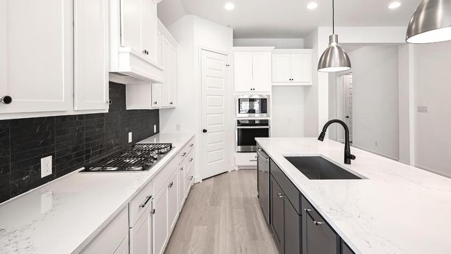 Kitchen with light wood-style flooring, white cabinets, light stone counters, appliances with stainless steel finishes, and hanging light fixtures | Image 17