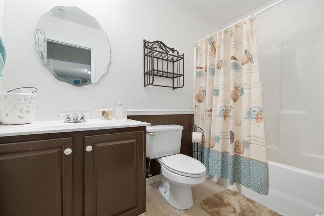 Full bath featuring a wainscoted wall, toilet, tile patterned floors, vanity, and shower / tub combo | Image 31