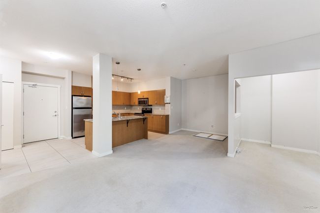 Kitchen with open floor plan, light carpet, a kitchen breakfast bar, stainless steel appliances, and brown cabinetry | Image 8