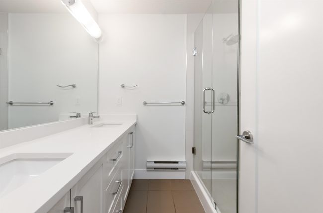 Full bath featuring a sink, double vanity, a stall shower, tile patterned flooring, and a baseboard radiator | Image 20