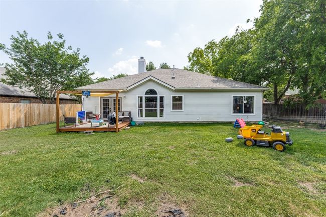 Rear view of house featuring a wooden deck, a chimney, roof with shingles, and an outdoor hangout area | Image 22