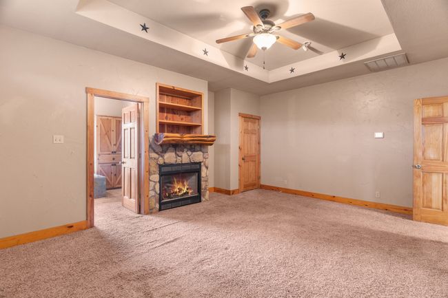 Unfurnished living room with baseboards, a raised ceiling, carpet, and a fireplace | Image 33