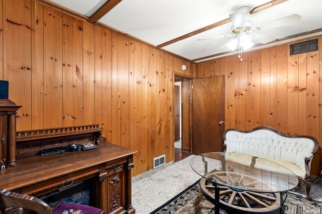 Carpeted office featuring visible vents, wooden walls, and a ceiling fan | Image 49