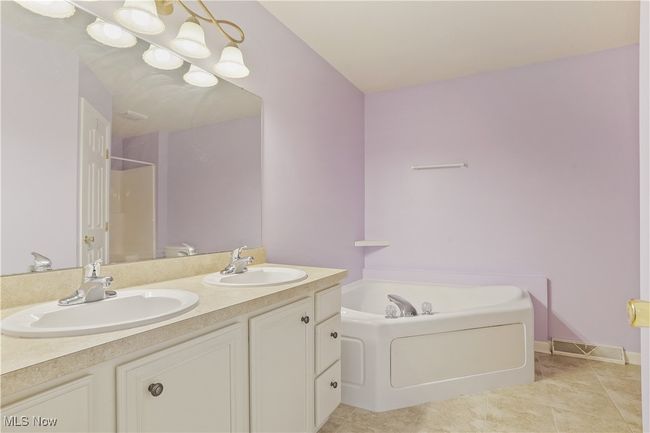 Bathroom featuring a garden tub, double vanity, a shower, and tile patterned flooring | Image 11