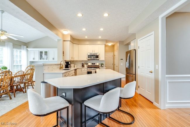 Kitchen featuring appliances with stainless steel finishes, a textured ceiling, a breakfast bar area, recessed lighting, and light countertops | Image 5