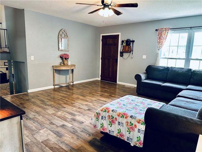 Living room with ceiling fan, wood finished floors, baseboards, and a textured ceiling | Image 9