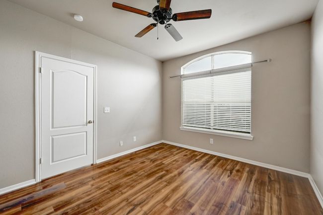Empty room with wood finished floors, a ceiling fan, and a smoke detector | Image 17