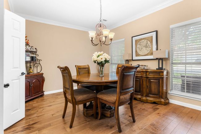 Dining area featuring a chandelier, ornamental molding, light wood finished floors, and healthy amount of natural light | Image 14