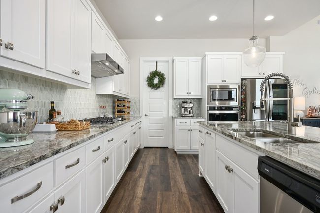 The kitchen is a highlight with stainless steel appliances, granite countertops, abundant cabinetry, and a large island with bar seating. | Image 4