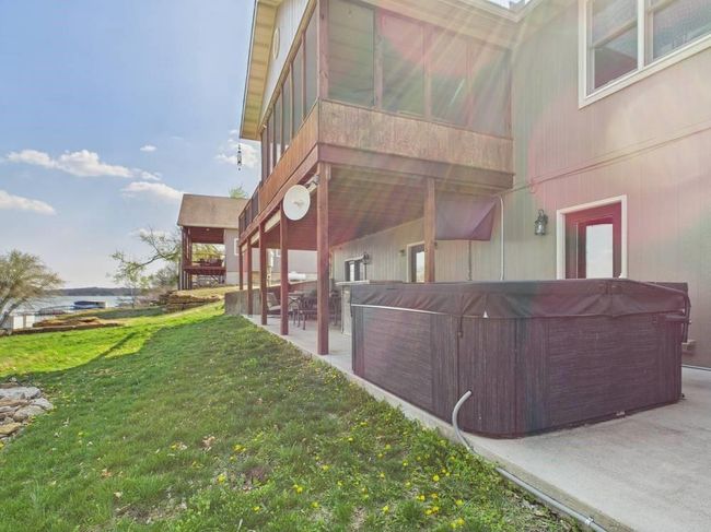View of back of property featuring a lawn, a lower patio, and a hot tub | Image 5