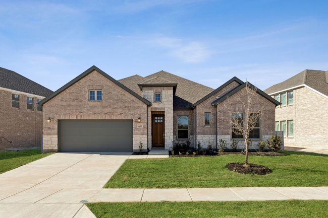 French country style house featuring brick siding, a front lawn, concrete driveway, roof with shingles, and a garage | Image 7