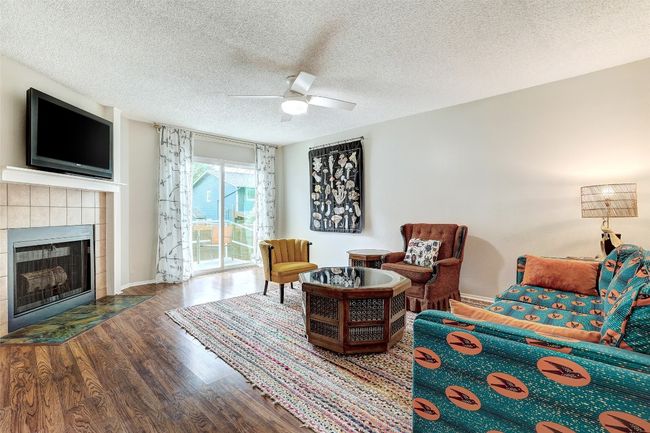 Sitting room with a tiled fireplace, wood finished floors, ceiling fan, a textured ceiling, and baseboards | Image 10