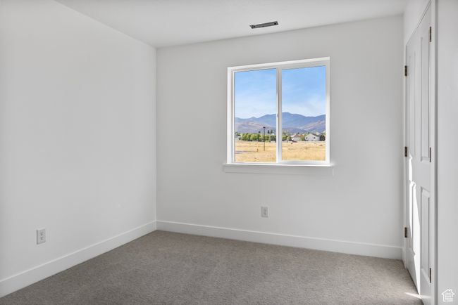 Unfurnished bedroom featuring a mountain view, baseboards, and carpet floors | Image 13
