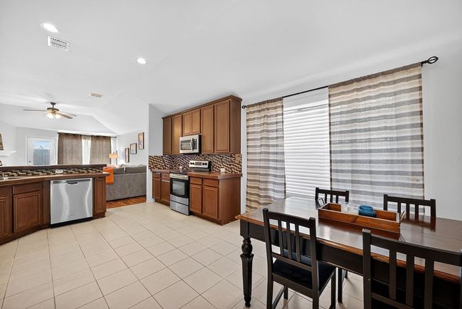 Kitchen featuring appliances with stainless steel finishes, a ceiling fan, lofted ceiling, light tile patterned flooring, and backsplash | Image 32