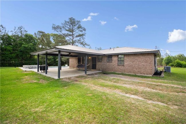 Back of house featuring brick siding, ceiling fan, an attached carport, a patio area, and a yard | Image 20