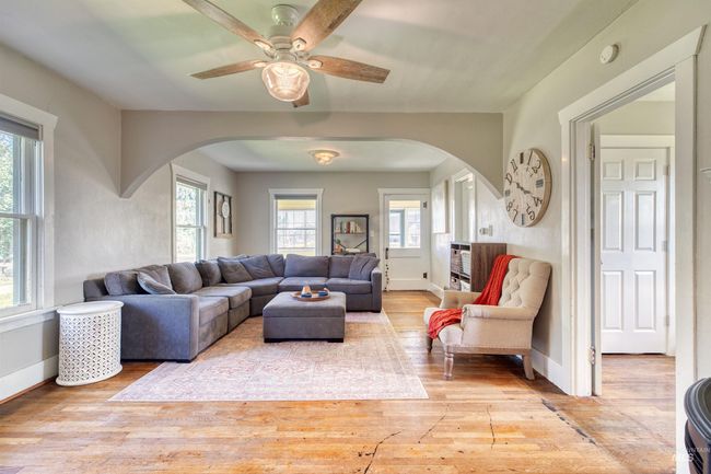 Living area with arched walkways, light wood-type flooring, and a ceiling fan | Image 12