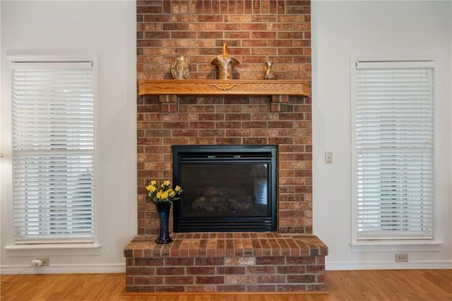 Room details featuring a brick fireplace, baseboards, and wood finished floors | Image 31