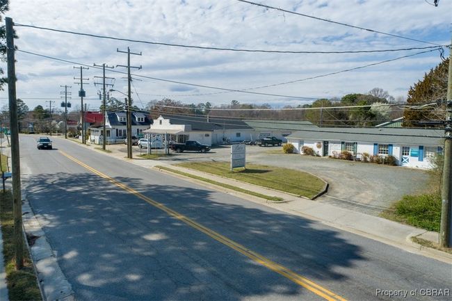View of asphalt road with curbs, a residential view, sidewalks, and street lighting | Image 16