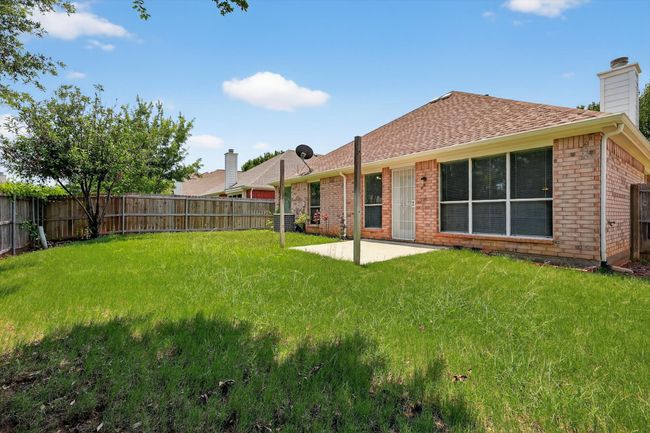 Rear view of house featuring a fenced backyard, a patio, a chimney, and a shingled roof | Image 19