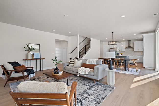 Living area featuring light wood-style flooring, recessed lighting, stairway, and a chandelier | Image 6