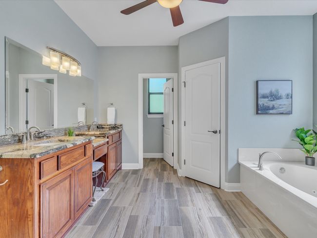 Bathroom featuring a ceiling fan, vanity, baseboards, and a bath | Image 19