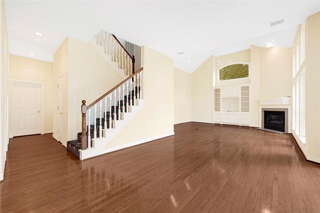 Spacious family room with high ceilings, a cozy fireplace, and a second staircase leading to the bedrooms. | Image 20