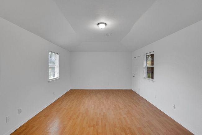 Empty room with baseboards, visible vents, lofted ceiling, and light wood-style floors | Image 11