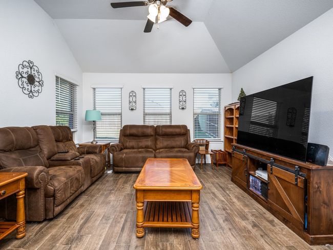 Living area featuring vaulted ceiling, a ceiling fan, and wood finished floors | Image 16