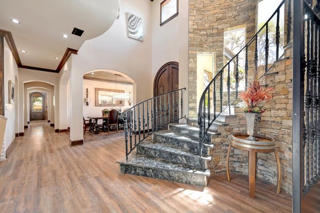 Entrance foyer with arched walkways, wood finished floors, a healthy amount of sunlight, and stairs | Image 6