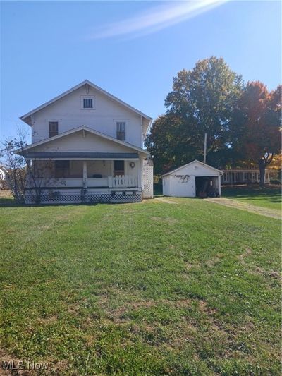 View of front facade with a porch, a front lawn, and an outdoor structure | Image 1