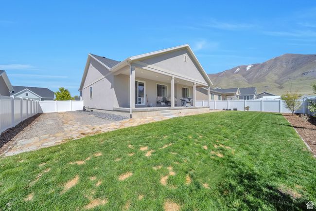 Rear view of house with a patio area, a lawn, a mountain view, and stucco siding | Image 25