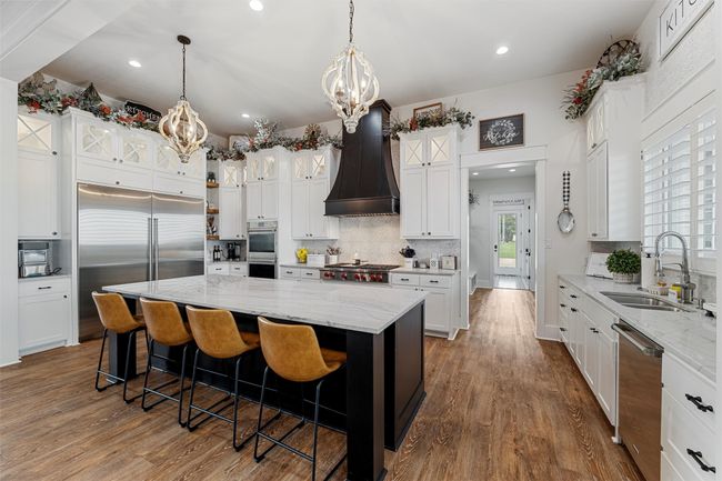 Kitchen featuring a sink, a chandelier, custom exhaust hood, stainless steel appliances, and dark wood-style flooring | Image 19