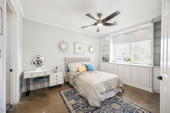 Downstairs Bedroom featuring concrete floors, a ceiling fan, ornamental molding, entertainment center, En Suite Full Bathroom and baseboards | Image 30