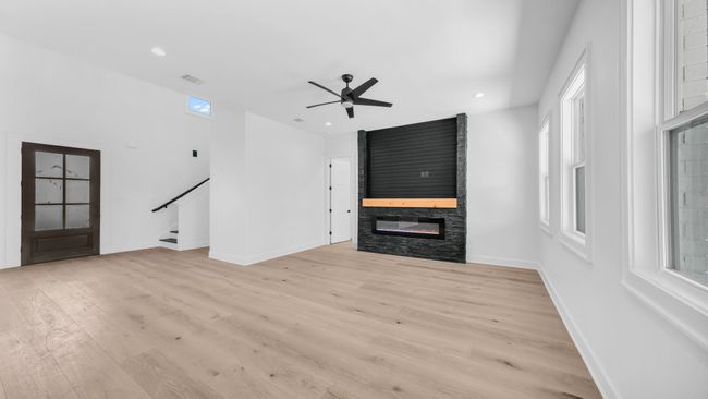Unfurnished living room with visible vents, a large fireplace, baseboards, stairs, and light wood-style floors | Image 8