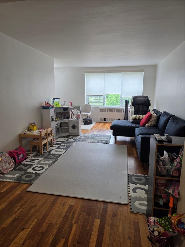 Living room with radiator heating unit and wood finished floors | Image 7