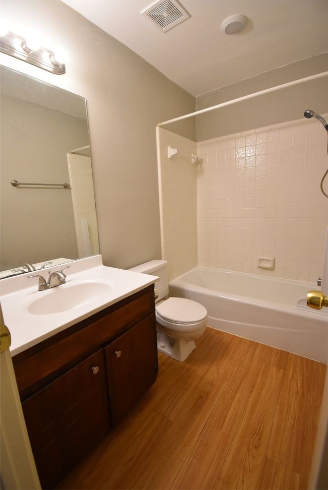 Bathroom with bathing tub / shower combination, vanity, and wood finished floors | Image 9