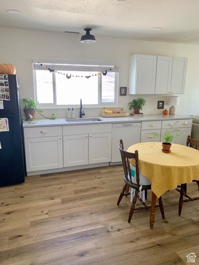 Kitchen with white cabinetry, white dishwasher, and black fridge | Image 2