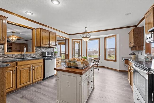 Kitchen with light wood-style flooring, a sink, appliances with stainless steel finishes, tasteful backsplash, and crown molding | Image 15
