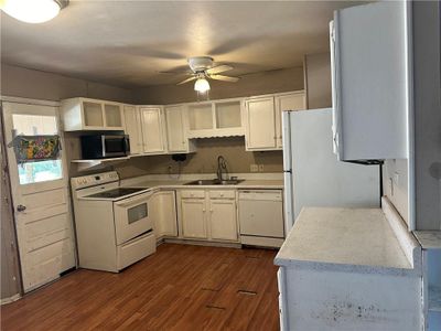 Kitchen with ceiling fan, white cabinets, sink, white appliances, and dark wood-type flooring | Image 2