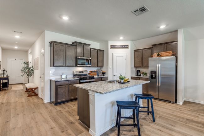 Kitchen View 2 featuring appliances with stainless steel finishes, built in cabinetry, light laminated wood plank floors, granite countertops, and recessed lighting | Image 8