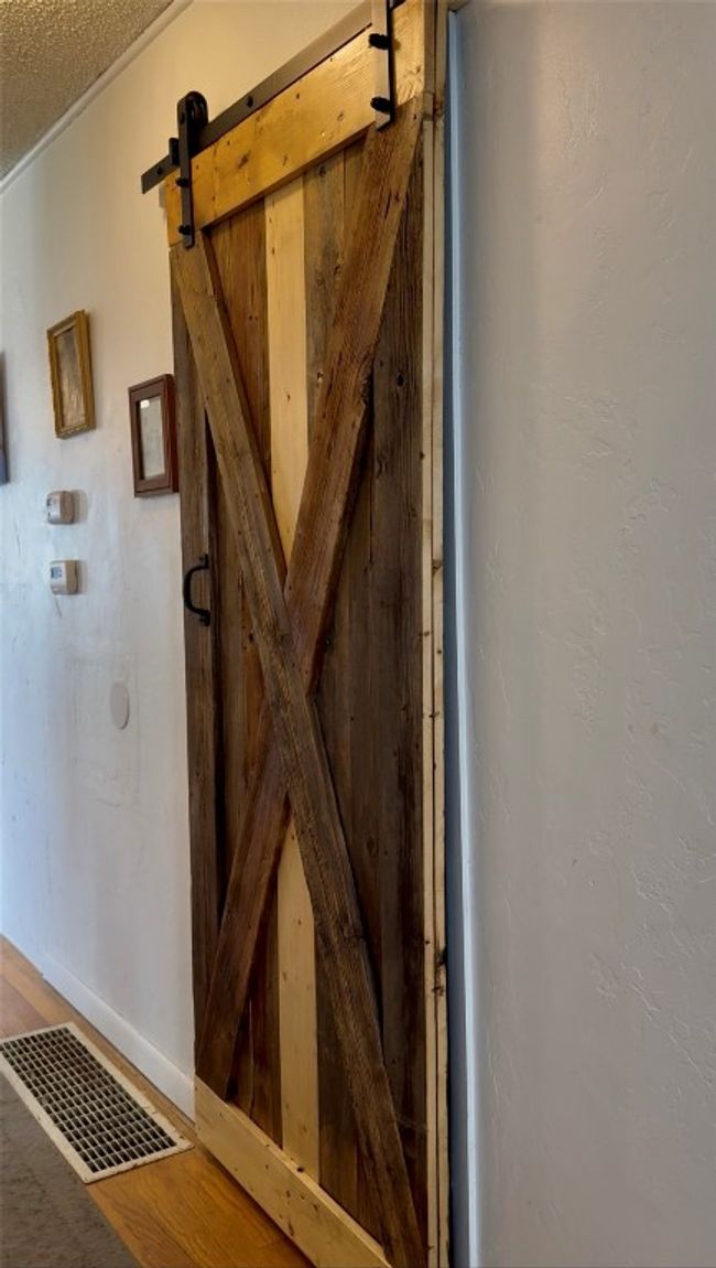 Detailed view of a barn door, a textured ceiling, and baseboards | Image 5
