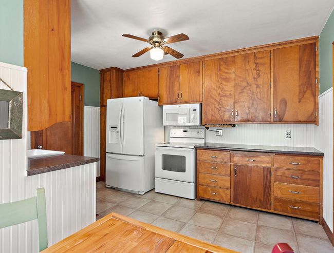 The kitchen has large cabinets and a hidden spice rack tucked under the hanging cabinet to the right of the stove. | Image 5