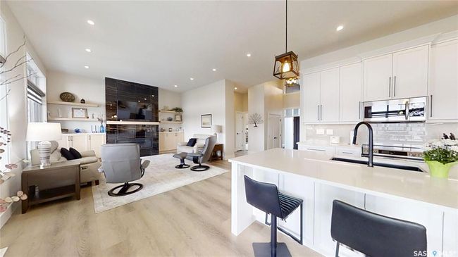 Kitchen with stainless steel appliances, light wood-style flooring, white cabinets, light countertops, and pendant lighting | Image 11