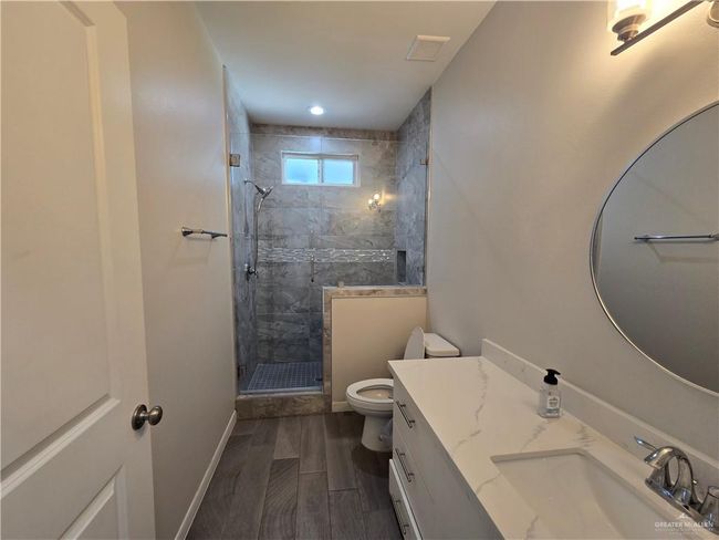 Bathroom featuring toilet, vanity, and a stall shower | Image 12