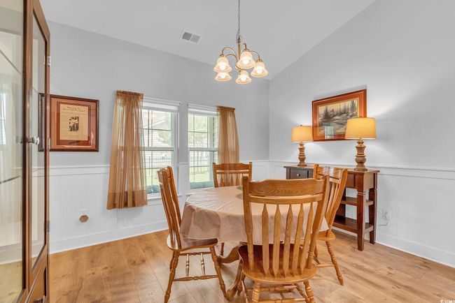 Dining space featuring a chandelier, light wood finished floors, visible vents, and a wainscoted wall | Image 14