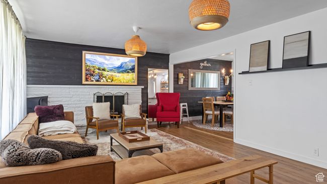 Living room featuring an accent wall, wood finished floors, wood walls, and baseboards | Image 6